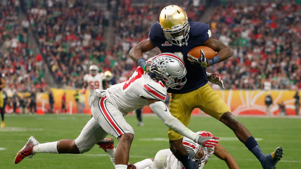 An Ohio State player tackling a Notre Dame player.