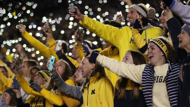 Michigan fans holding up their cell phones during a football game.