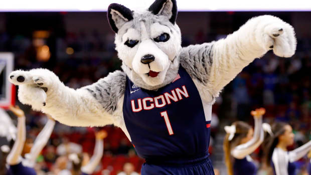 UConn Huskie's mascot running with both arms up.