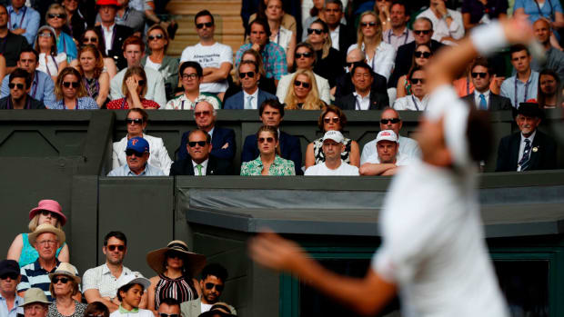 Roger Federer serves in front of his wife at Wimbledon.