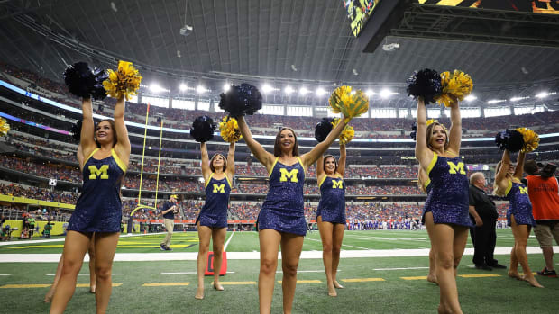 Michigan Wolverines cheerleaders waving pompoms during a game.