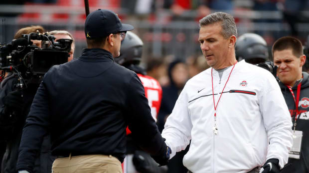 Head coach Urban Meyer of the Ohio State Buckeyes and Head coach Jim Harbaugh of the Michigan Wolverines shake hands on the field prior to their game.