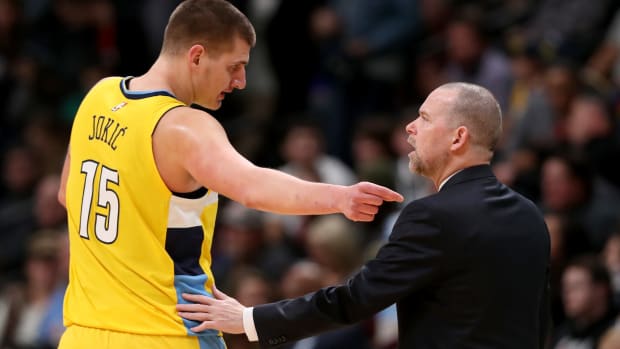 Denver Nuggets head coach Mike Malone talks to star center Nikola Jokic during a game.