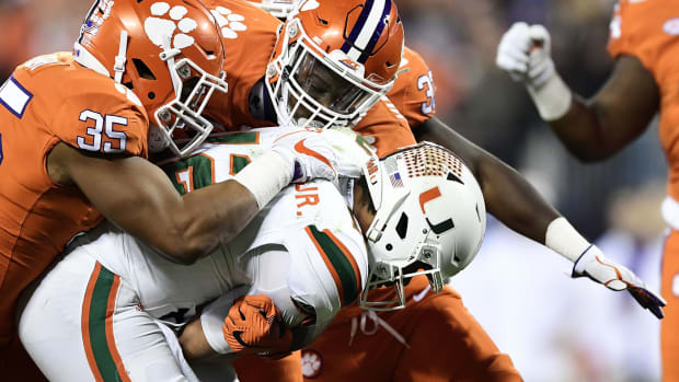Clemson football players tackle a Miami Hurricane during the ACC Championship college football game.
