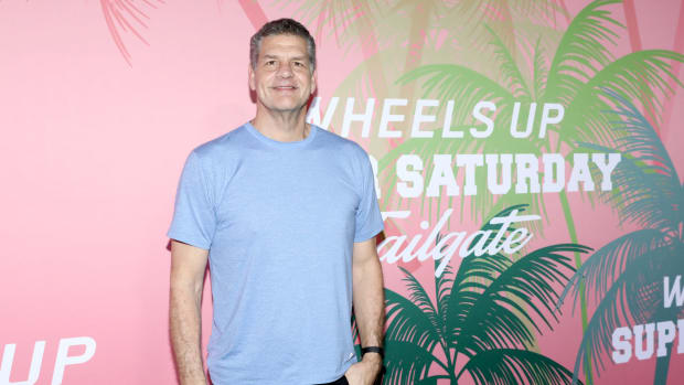 Mike Golic stands in front of a billboard.