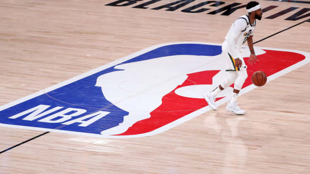 Utah Jazz PG Mike Conley dribbles the ball on the NBA logo at halfcourt.