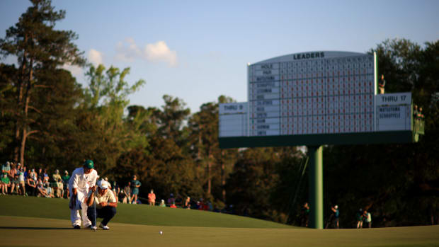 Hideki Matsuyama and his caddie line up a putt at The Masters.
