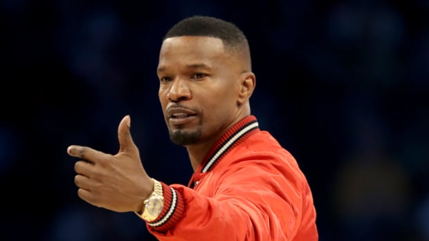 A closeup of Jamie Foxx wearing a red jacket at the NBA All-Star game.