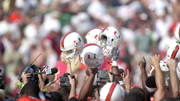 Miami football helmets held up by Hurricanes players.