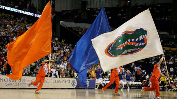 Florida Gators cheerleaders waving flags during a basketball game.
