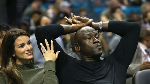 Michael Jordan sitting with his wife Yvette Prieto at a Hornets game.