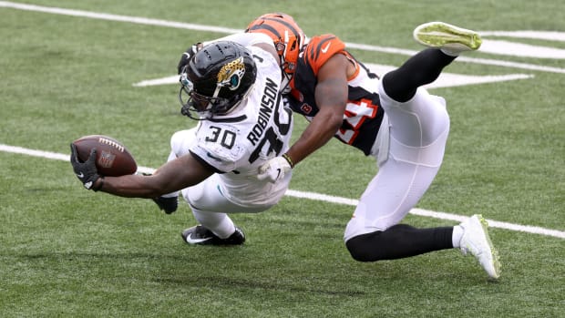 Jacksonville Jaguars running back James Robinson reaches with the ball as he is tackled.