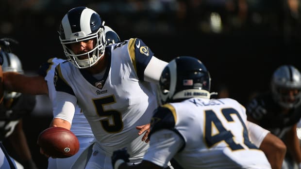 Rams quarterback Blake Bortles hands the ball to a running back.