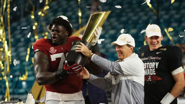 Nick Saban and Alex Leatherwood lift the national title trophy.