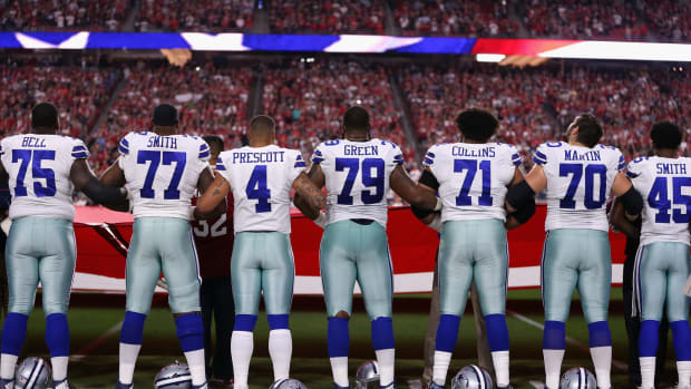 A photo of the Dallas Cowboys locking arms during the National Anthem, including Dak Prescott and his offensive line.
