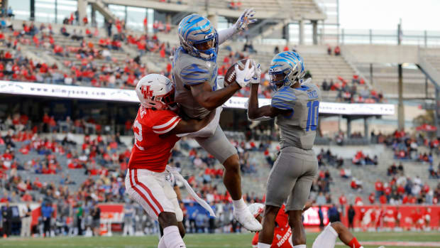 Memphis football's Antonio Gibson leaps for a touchdown against a Houston defender.