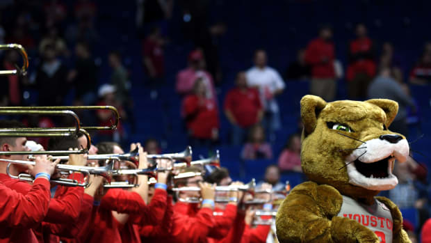 A closeup of the Houston Cougar's mascot standing besides the band.