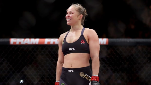 Ronda Rousey in the octagon with a huge smile on her face.