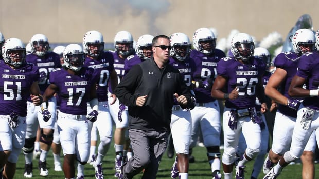 Northwestern coach Pat Fitzgerald leading his team onto the field.