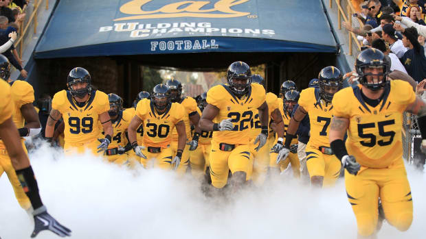 Cal's football team running through smoke ahead of a Pac-12 football game.