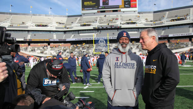 Head coach Kirk Ferentz of the Iowa Hawkeyes visits with head coach Lovie Smith of the Illinois Fighting Illini before their match-up