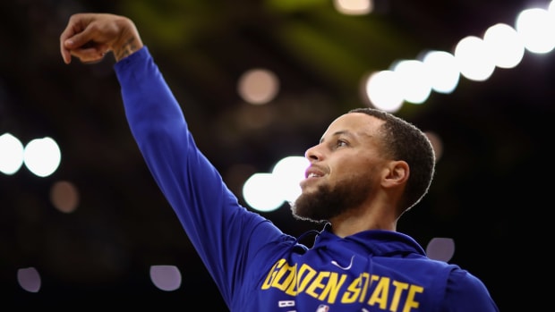 Steph Curry warming up in a Golden State Warriors hoodie.