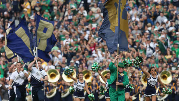 Notre Dame's mascot running on the field with a flag.