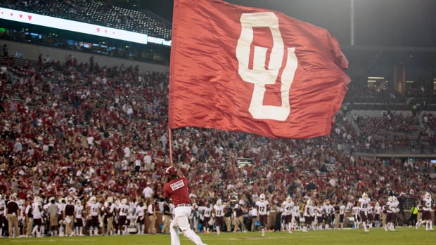 An Oklahoma cheerleader running with an OU flag.