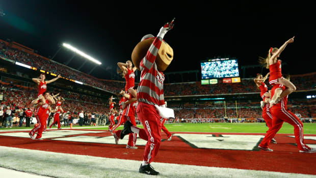 Brutus Buckeye running on the field with the Ohio State cheerleaders
