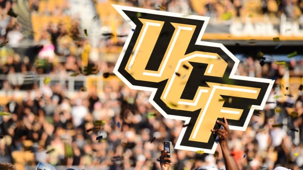 UCF Football players holding a UCF football sign in the air.