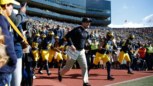 Head coach Jim Harbaugh of the Michigan Wolverines leads the team onto the field to play the Illinois Fighting Illini.