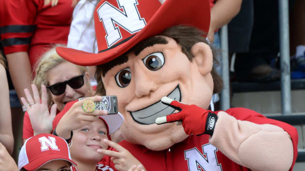Nebraska's mascot takes picture with a fan.