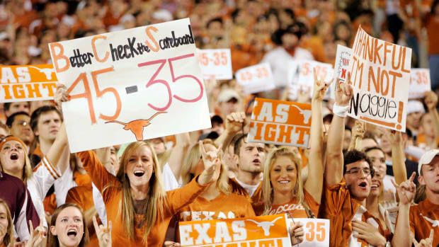Texas Longhorns fans holding signs during a game.