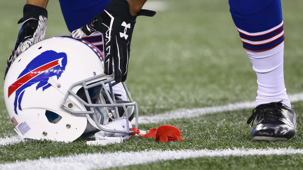 A Buffalo Bills player picking up his helmet off of the field.