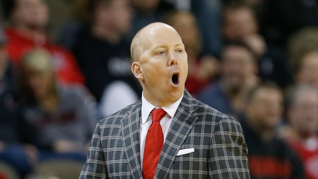 Mick Cronin with his mouth wide open while wearing a red tie.