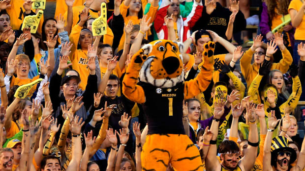 Missouri's mascot standing with the team's fans during a football game.