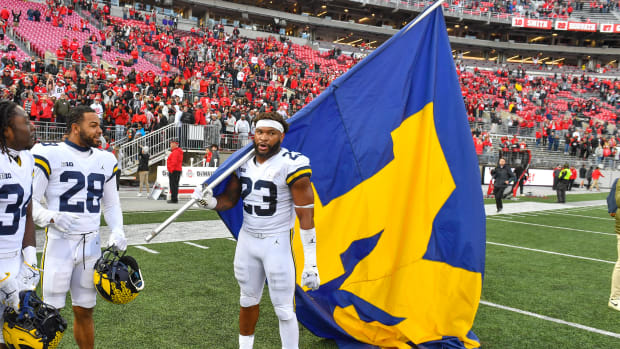 A Michigan football player holding the school's flag in Ohio Stadium.