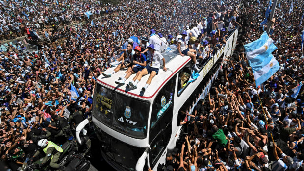 Fans of Argentina cheer as the team parades on board a bus after winning the Qatar 2022 World Cup tournament in Buenos Aires, Argentina on December 20, 2022. - Millions of ecstatic fans are expected to cheer on their heroes as Argentina's World Cup winners led by captain Lionel Messi began their open-top bus parade of the capital Buenos Aires on Tuesday following their sensational victory over France. (Photo by Luis ROBAYO / AFP) (Photo by LUIS ROBAYO/AFP via Getty Images)