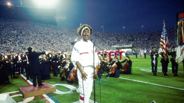 TAMPA, FL - JANUARY 27:  Whitney Houston sings the National Anthem during the pregame show at Super Bowl XXV while tens of thousands of football fans wave tiny American flags in an incredible outburst of patriotism during the Persian Gulf War on 01/27/1991.  (Photo by Michael Zagaris/Getty Images)
