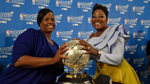 Draymond Green and Kevin Durant's moms holding the trophy following an NBA game.