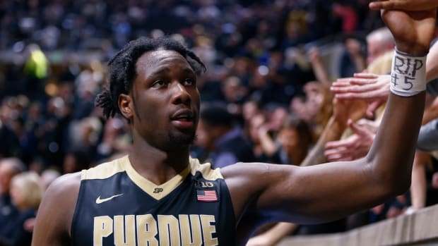 Purdue star Caleb Swanigan high-fives a fan while leaving the court after a game.