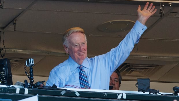 Legendary announcer Vin Scully waves to the crowd during a playoff game.