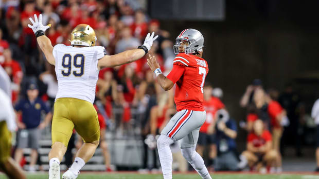 C.J. Stroud from Ohio State prepares to throw a pass with a Notre Dame defender closing in on him.