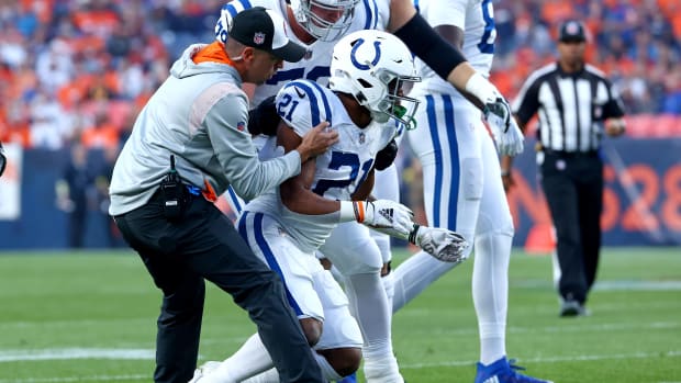 DENVER, COLORADO - OCTOBER 06: Nyheim Hines #21 of the Indianapolis Colts is helped to his feet by #79 after being hit  during a game against the Denver Broncos at Empower Field At Mile High on October 06, 2022 in Denver, Colorado. (Photo by Justin Tafoya/Getty Images)