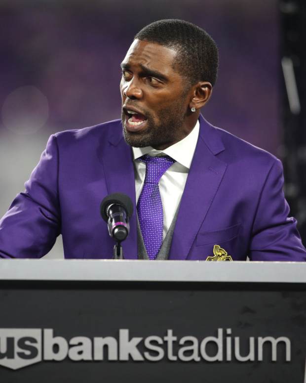 Randy Moss speaking at a podium.