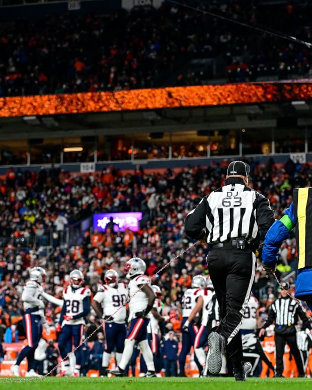 DENVER, COLORADO - DECEMBER 24:  Down judge Mike Carr #63 runs onto the field with the first down marker to measure the spot of the ball with the chains in the second quarter of a game between the Denver Broncos and the New England Patriots at Empower Field at Mile High on December 24, 2023 in Denver, Colorado. (Photo by Dustin Bradford/Getty Images)