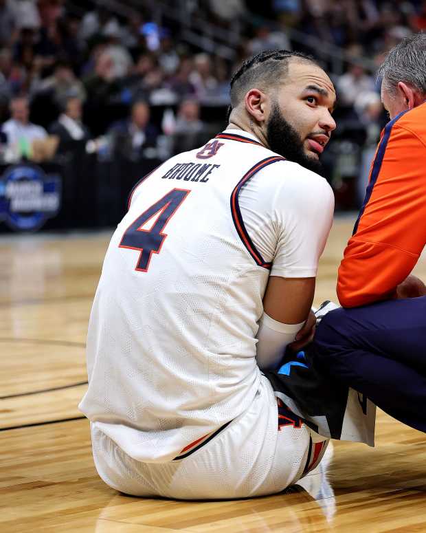 Johni Broome sits on the floor with a trainer after getting injured.