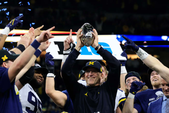 Jim Harbaugh raises the Big Ten Championship trophy above his head.