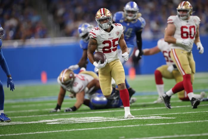 Elijah Mitchell runs with the football.