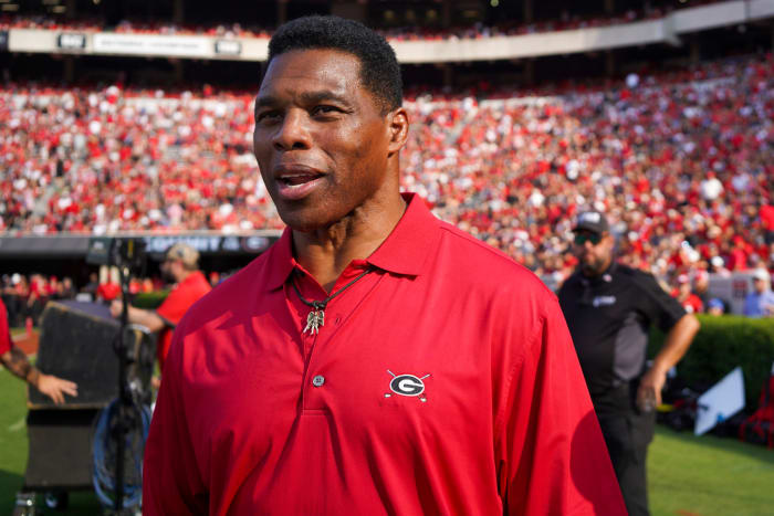 Former Georgia running back Herschel Walker looks on from the sidelines as a spectator during a game.